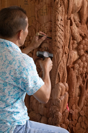 carpenter carving wooden pillars in a temple in Thailandの写真素材