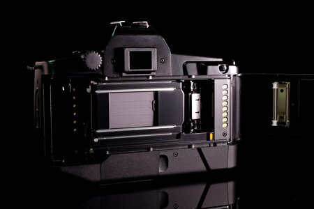 Retro film camera, close-up, back view, on black background.