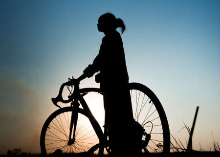 silhouette of young woman with bicycle outdoorの写真素材