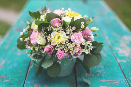 Image of flowers arrangement eustoma, spray yellow and violet roses, pink carnations, eucaliptus, waxflowers. Mixed flowers bouquet in mint tea cup on the turquoise wooden tableの写真素材