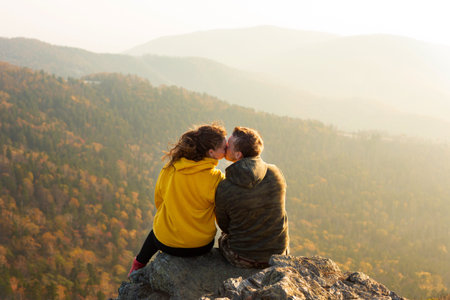 Couple in love sitting at the top of the mountain and watching autumn landscape. Sunsetの写真素材
