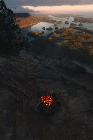 Campfire above coastal view with islands at sunsetの写真素材