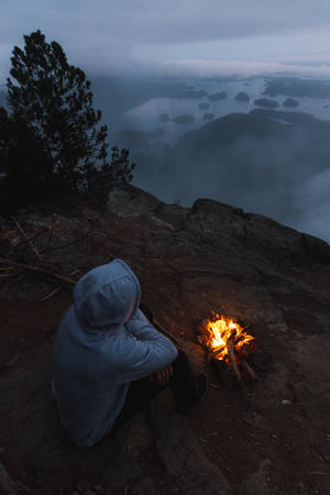 Man near campfire above coastal view with islands at nightの写真素材