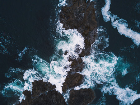 Aerial shot of waves hitting rocks