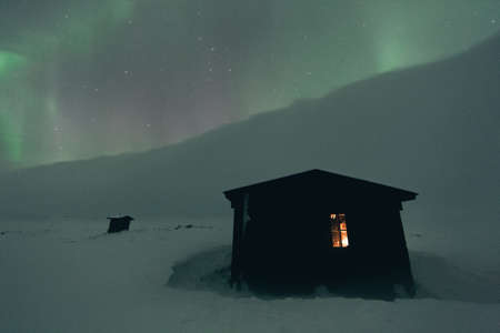 Blizzard at night with visible aurora borealis in snow coveres landの写真素材