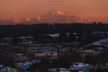 Snow covered forest and mountains illuminated by sunriseの写真素材
