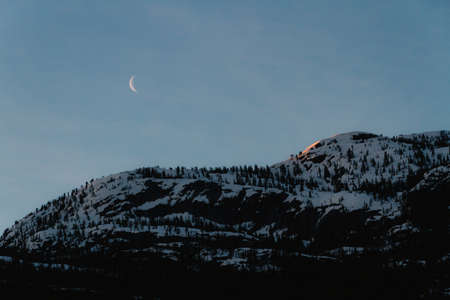 Morning orange light on mountains with moonの写真素材