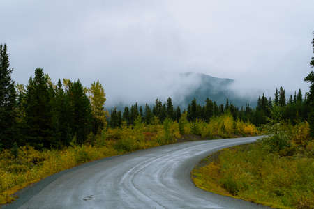 Scenic highway surrounded by mountains and trees in autumn season in Alaskaの写真素材