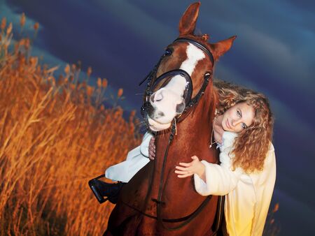 bride ride on red  horse at sunsetの写真素材