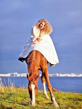 bride ride on red  horse in gulf at eveningの写真素材