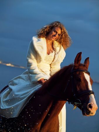 bride ride on red  horse in gulf at eveningの写真素材