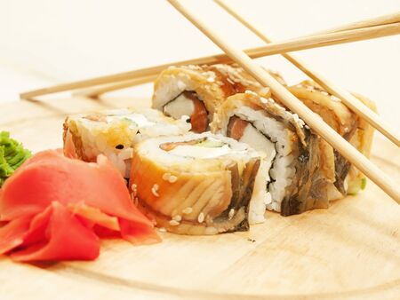 sushi rolls with omelette and eel and chopsticks on desk closeupの写真素材