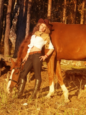 Young cowgirl with her red horse at sunset. の写真素材