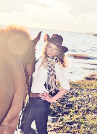  Cute cowgirl with her horse at gulf.の写真素材