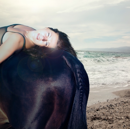 sexy women with black horse  at the seaの写真素材