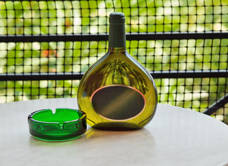 Bottle of white wine with ashtray at the tableの写真素材