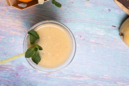 healthy fresh yellow fruit mango smoothie at blue tableの写真素材