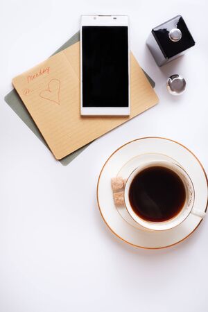 Cup of coffee with diary and smartphone around white background. Flat layの写真素材