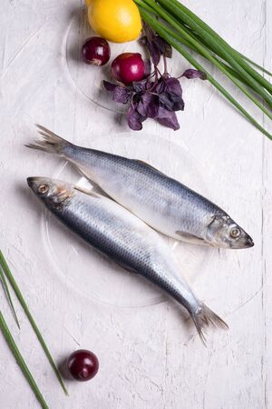 salted whole herring  on a transporant plate with defferent onions and seasonings. served in Scandinavian style. Typical cooking fish in Scandinavian countries.の写真素材