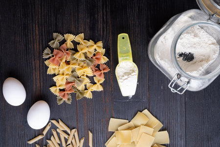 variety of types and shape of italian pasta on dark wooden table. dry pasta background