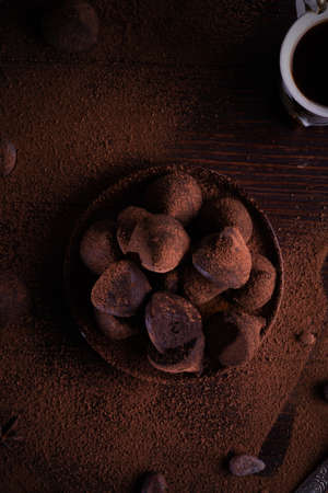 Delicious chocolate truffles around ingredients with natural cocoa beans, powder, cacao butter, cane sugar and cup of coffee.の写真素材
