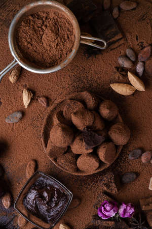 art background with healthy delicious dark truffles, chocolate and ingridients: natural cocoa beans, powder, chocolate, almonds nuts and ripe cherry. healthy sweets concept. flat layの写真素材