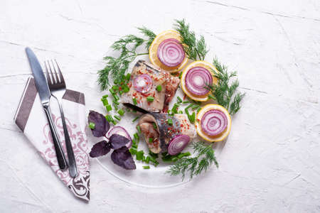 marinated herring roll fillet on a transporant plate with green onion, lemon and seasonings. served in Scandinavian style. Typical cooking fish in Scandinavian countries. copy spaceの写真素材