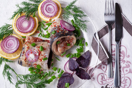 marinated herring roll fillet on a transporant plate with green onion, lemon and seasonings. served...