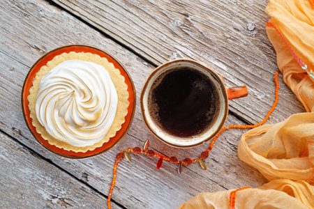 cup of coffee with delicious cream cake with orange scarf around white old style wooden background. close up. lifestyle conceptの写真素材
