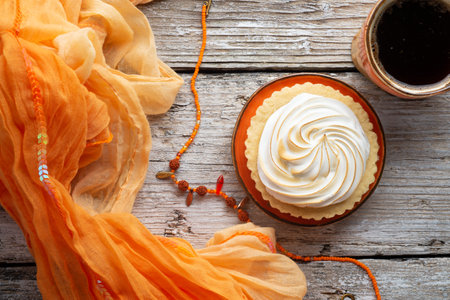 cup of coffee with delicious cream cake with orange scarf around white old style wooden background. close up. lifestyle conceptの写真素材