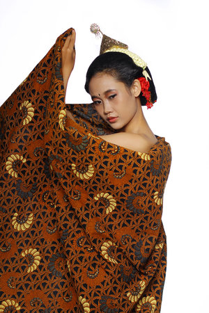 Beautiful javanese woman wearing a lurik. Traditional javanese costume. Woman sitting on a chair...