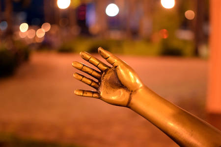 A fragment, the hand of a statue, a bronze hand reaching out to another person, palm. Concept. Night timeの写真素材