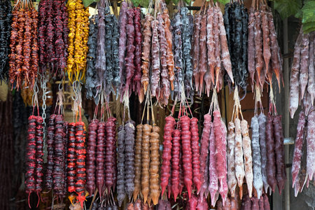 Churchkhela with walnuts red, yellow and brown hanging on a thread on the counter. Traditional sweets in Georgia. Delicious and healthy Georgian desserts.の写真素材