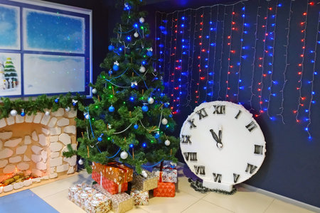 Christmas tree with toys, lit garlands and New Year's gifts under it. Christmas garlands on the wall...