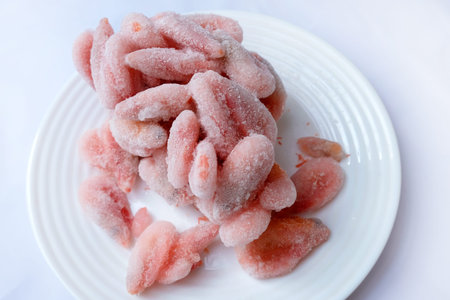 Frozen boiled shrimps lie on a white plate. Shrimps in ice glaze are defrosted on a plate.