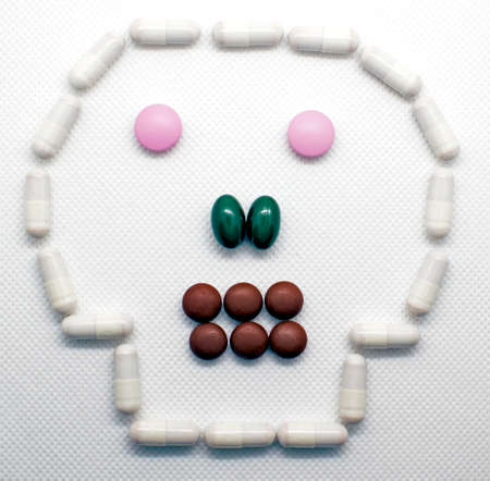The concept of health care, medical devices, treatment of diseases, the benefits and harm of tablets. form of the skull paved with pills on a white background.の写真素材