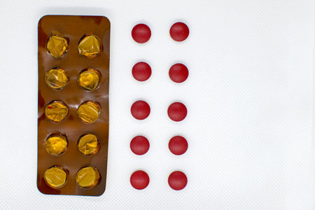 red pills and an empty stack of pills on a white background, concept. liver treatment, health care