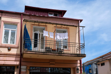 On the ropes hang white t-shirts after washing. Balcony on the second floor of the building with a...