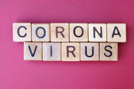 The inscription corona virus on a dark pink background, top view. The epidemic of the covid-19 virus. Wooden cubes with letters.の写真素材