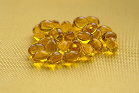 Vitamin D in yellow jelly capsules. Small yellow capsules on a yellow background. A slide of pills,...
