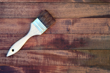Wooden boards covered with stain top view. A brush with a wooden handle and natural bristles against the background of painted wooden planks. Painting work, mockup.の写真素材
