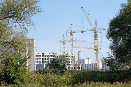 The process of building a new district of residential buildings. Cranes and unfinished houses among...
