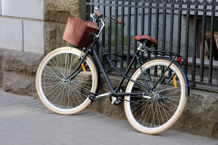 A leisure bike with a brown basket is parked near a metal fence. City bike for walking and shopping trip. Bicycle theft unreliable locks.の写真素材