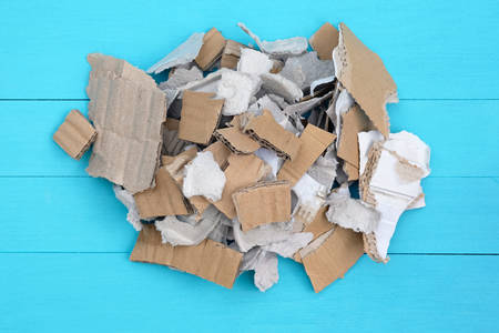 Pieces of cardboard on a blue wood background. Waste paper recycling. Pieces of cardboard boxes, paper stacked in a pile top view.の写真素材