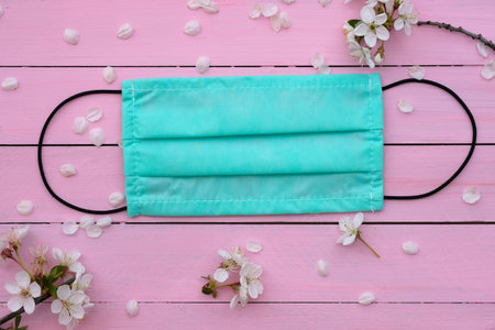green medical mask on a pink background top view. face mask, protection against viruses and bacteria...