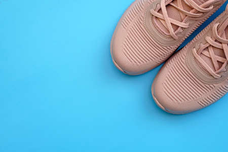 Pink sneakers on a blue background top view. Women's sports shoes in powdery color. Beige sneakers The concept of a healthy active lifestyle and nutrition, daily exercise and willpower.の写真素材
