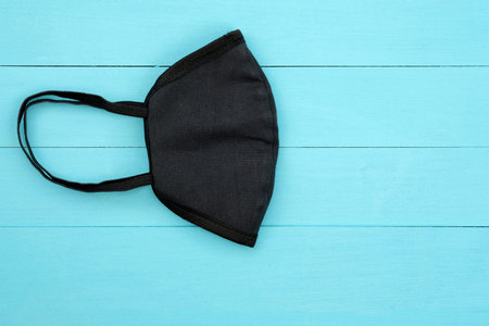 Black cotton mask folded in half. Do-it-yourself face mask made of fabric. Black handmade mask with...