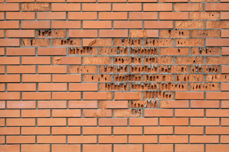 Red brick crumbles in the wall. The facing brick crumbles. Destruction of brickwork on the wall....