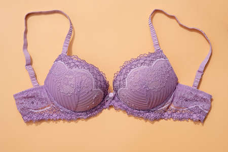 Lilac bra with removable straps on a beige background top view. Sexy bra with push up. Lace underwear for women.の写真素材