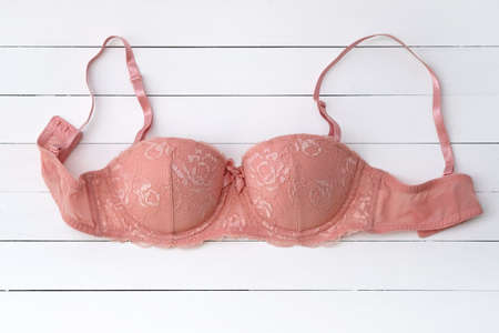 Pink lace bra top view. Bra with push up on a white wooden background. Classic sexy lingerie. Beautiful full coverage bra. lingerie store concept, sale, special offerの写真素材